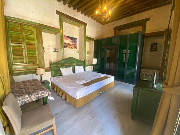 A bedroom with a bed, a desk, and a chair. There is a painting on the wall and a chandelier above the bed. - Hanehan Butik Otel (Sanliurfa)