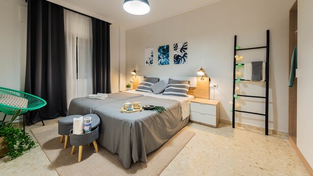 Een moderne slaapkamer met een bed, nachtkastjes, een stoel en kunst aan de muur.