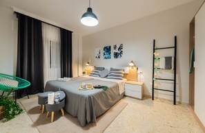 A modern bedroom with a bed, bedside tables, a chair, and artwork on the wall. - Nordik Rooms (Málaga)