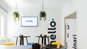 Een moderne keuken met een groot eiland, hangende planten en een televisie waarop 'nordik rooms' staat.