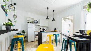 Een moderne keuken met witte kasten, een zwart aanrecht en kleurrijke stoelen.