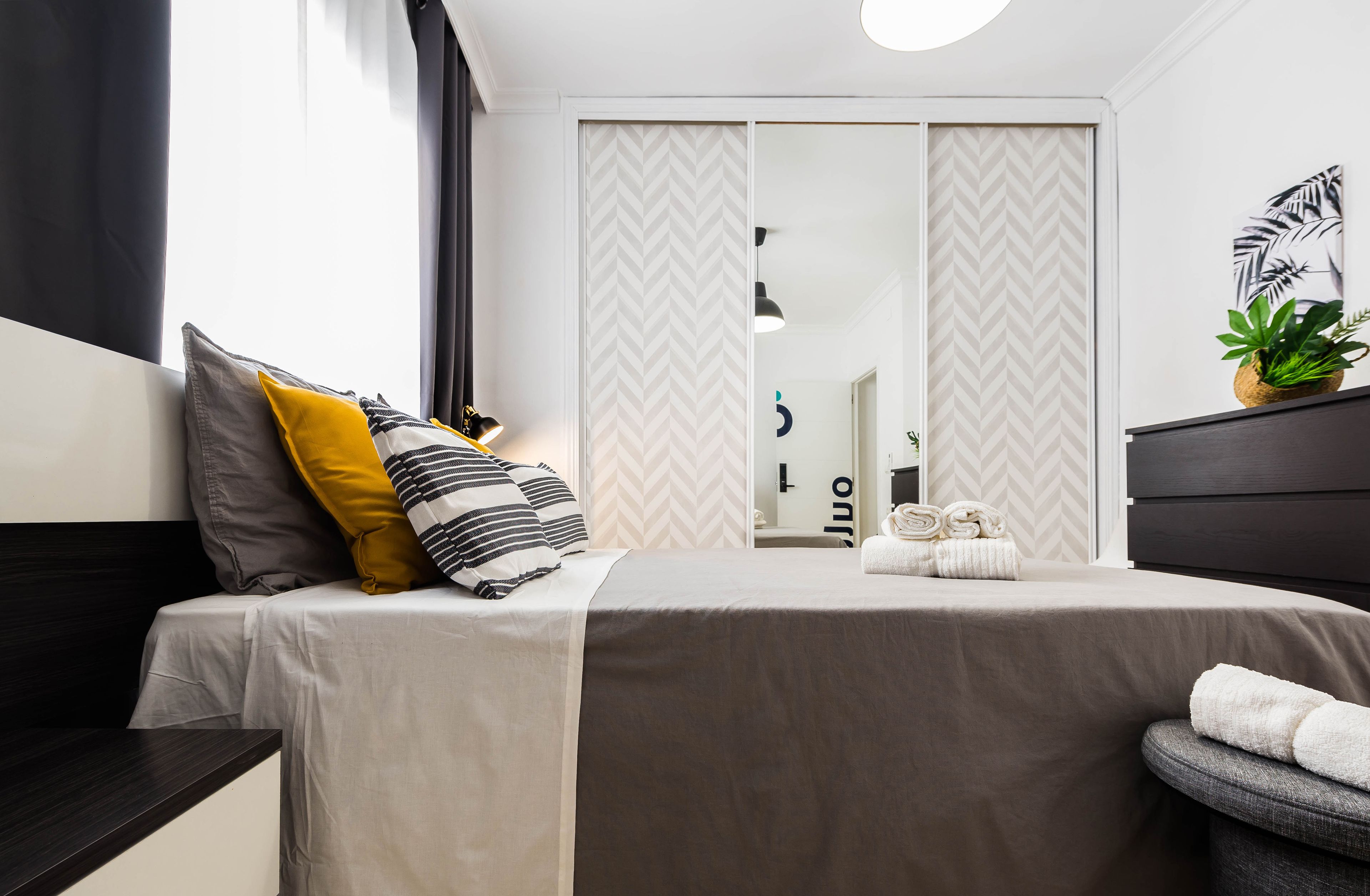 Ein modernes Schlafzimmer mit Bett, Nachttisch und Spiegel.