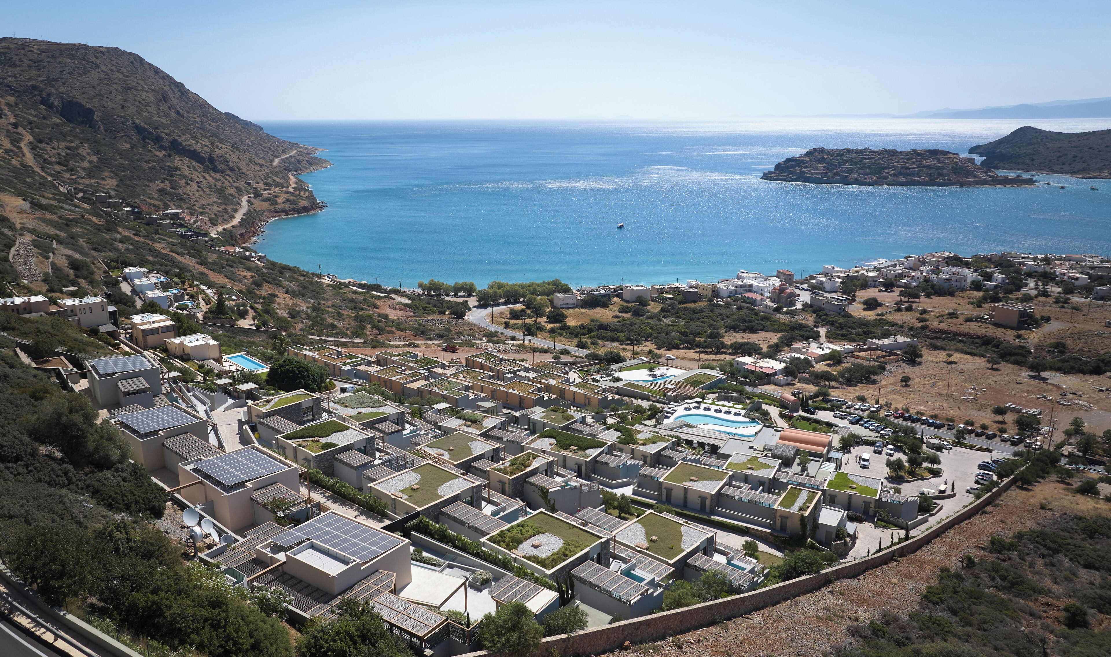 A coastal residential area with modern houses, a swimming pool, and a view of the sea.