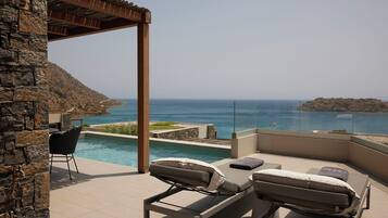 A poolside area with lounge chairs and a pergola overlooking a coastal view.
