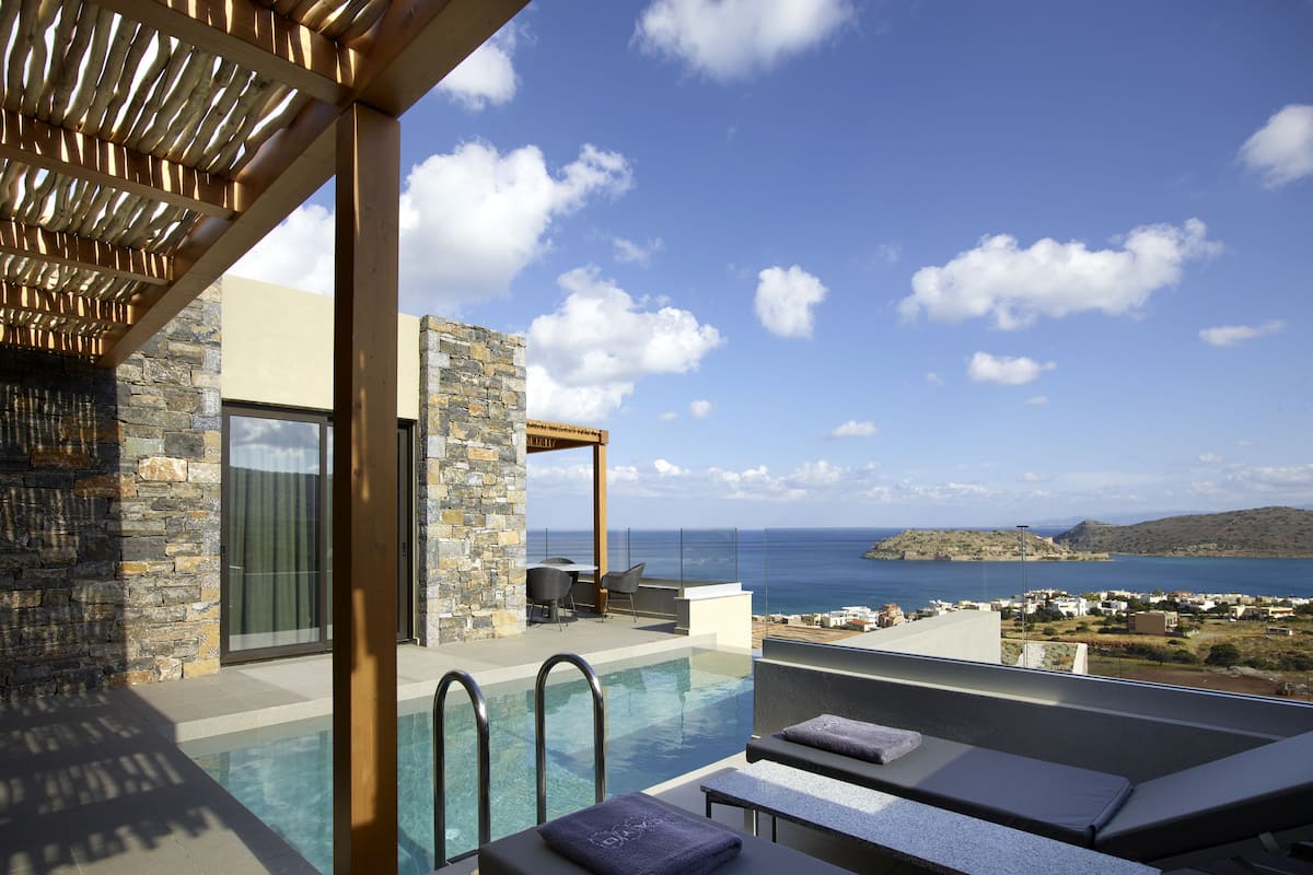A rooftop infinity pool with lounge chairs and a stone wall.