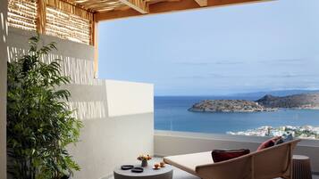 A balcony with a view of the sea, a potted plant, and a seating area with a table and chairs.