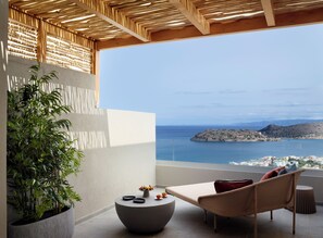 A balcony with a view of the sea, a potted plant, and a seating area with a table and chairs. - Cayo Exclusive Resort & Spa (Agios Nikolaos)