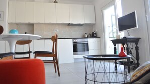 A modern kitchen with white cabinets, a built-in oven, and a large window. - Zennova 9 City Center Pearl (Thessaloniki)