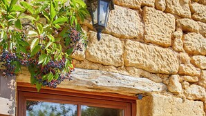 A stone building with a wooden door and a window. - La Suite Troglodyte (Vitrac)