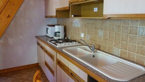 A kitchen with a gas stove, microwave, sink, and wooden cabinets.