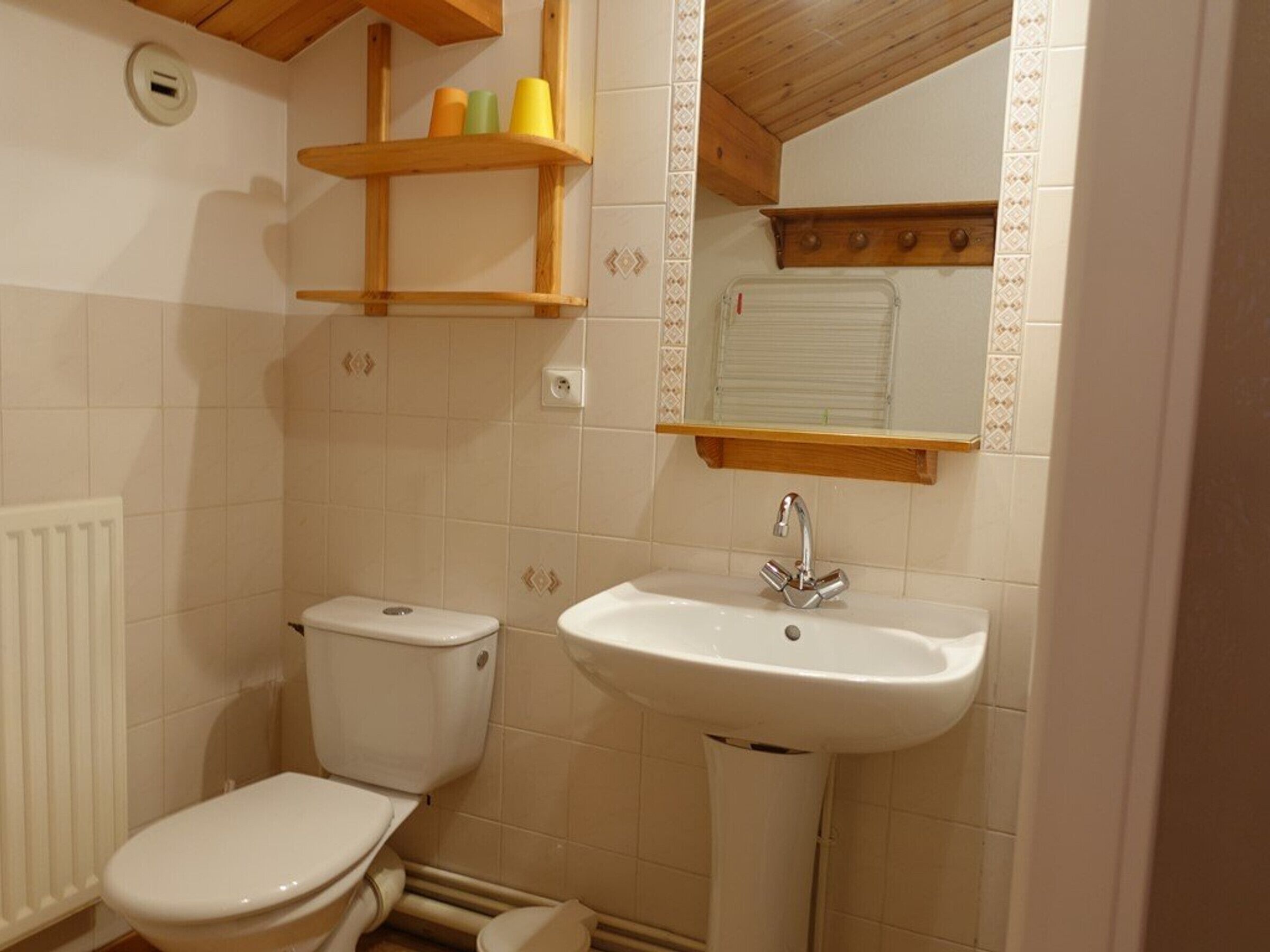 Un baño pequeño con un inodoro, un lavabo y una repisa con artículos de aseo.