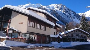 A building with a snow-covered roof and a mountain backdrop.