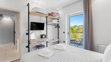 Une chambre d’hôtel moderne équipée d’un lit, d’une télévision, d’un bureau et d’un balcon avec vue.