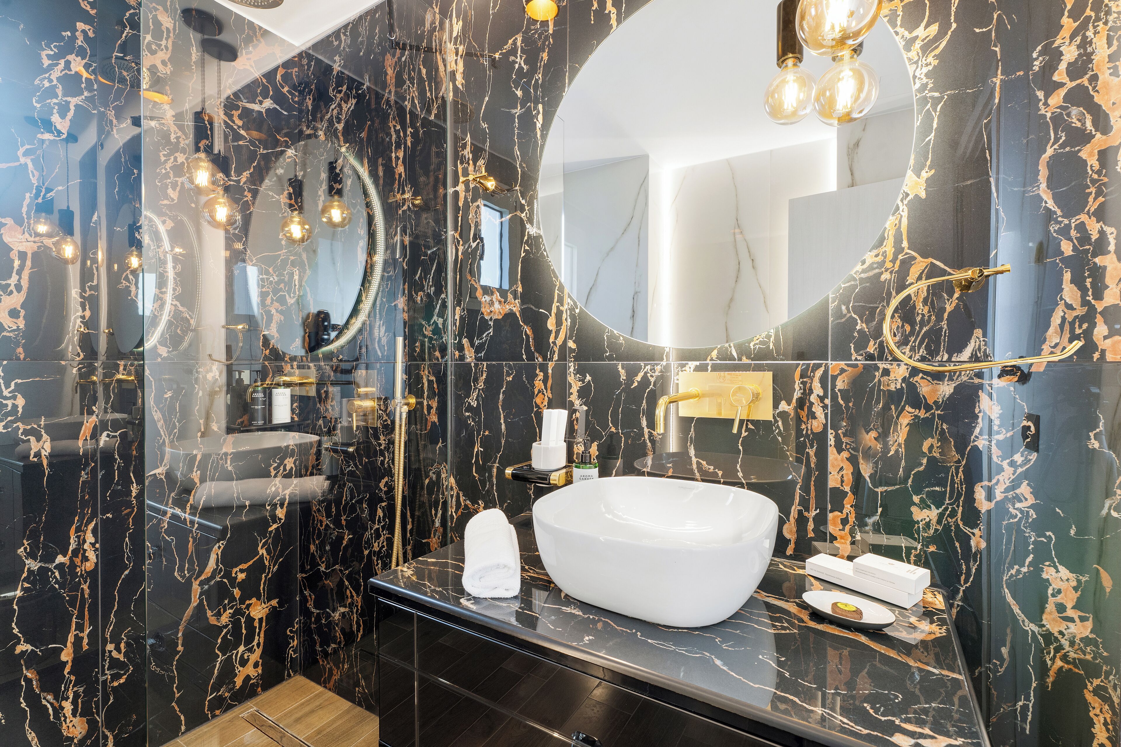 Un baño moderno con un lavamanos ovalado grande, un espejo y una zona de ducha con mampara de vidrio.