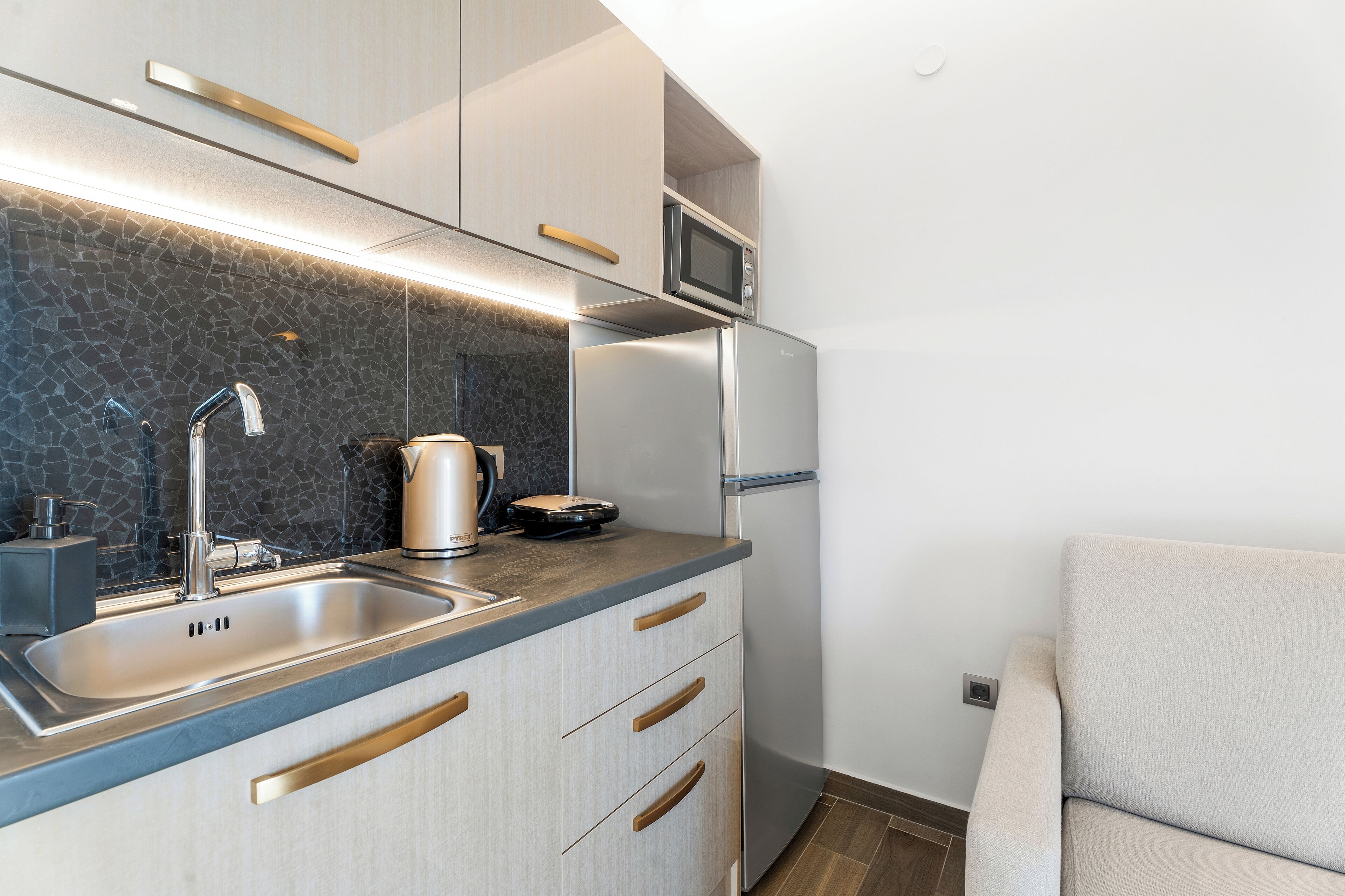 A modern kitchen with a built-in microwave, stainless steel refrigerator, and a coffee maker on the counter.