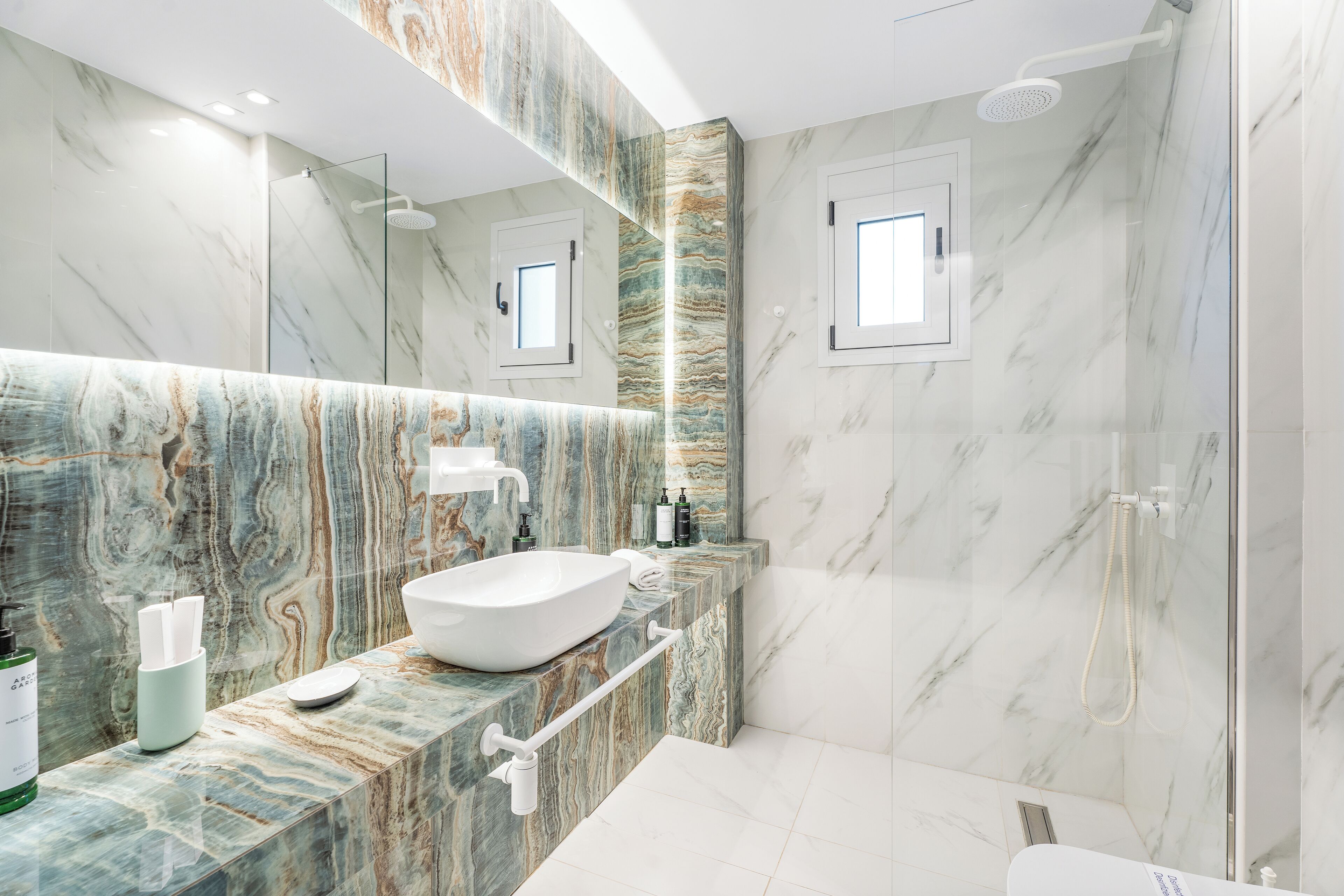 A modern bathroom with a marble vanity, a large mirror, and a shower area.
