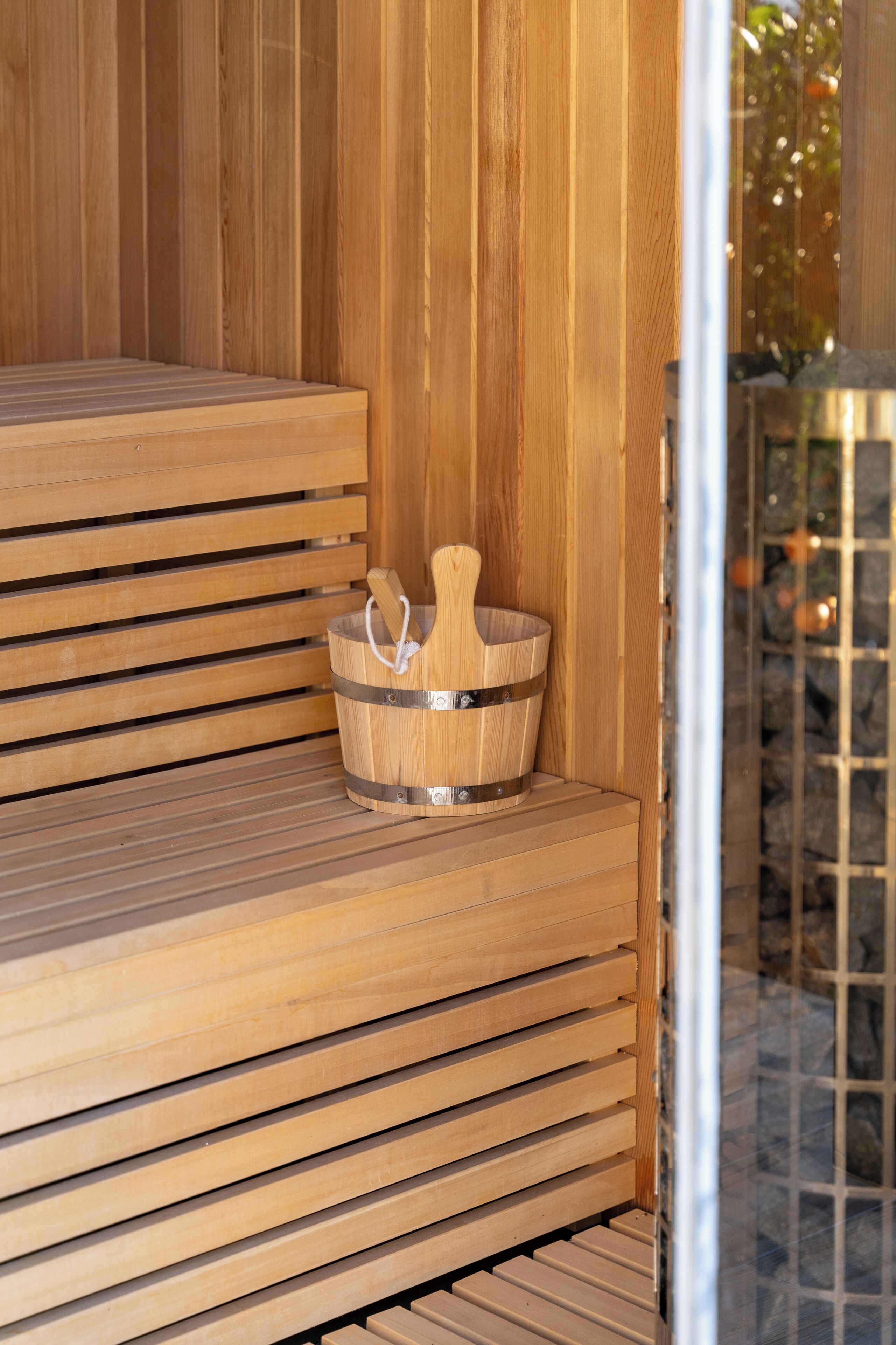 A wooden sauna bench with a metal bucket.