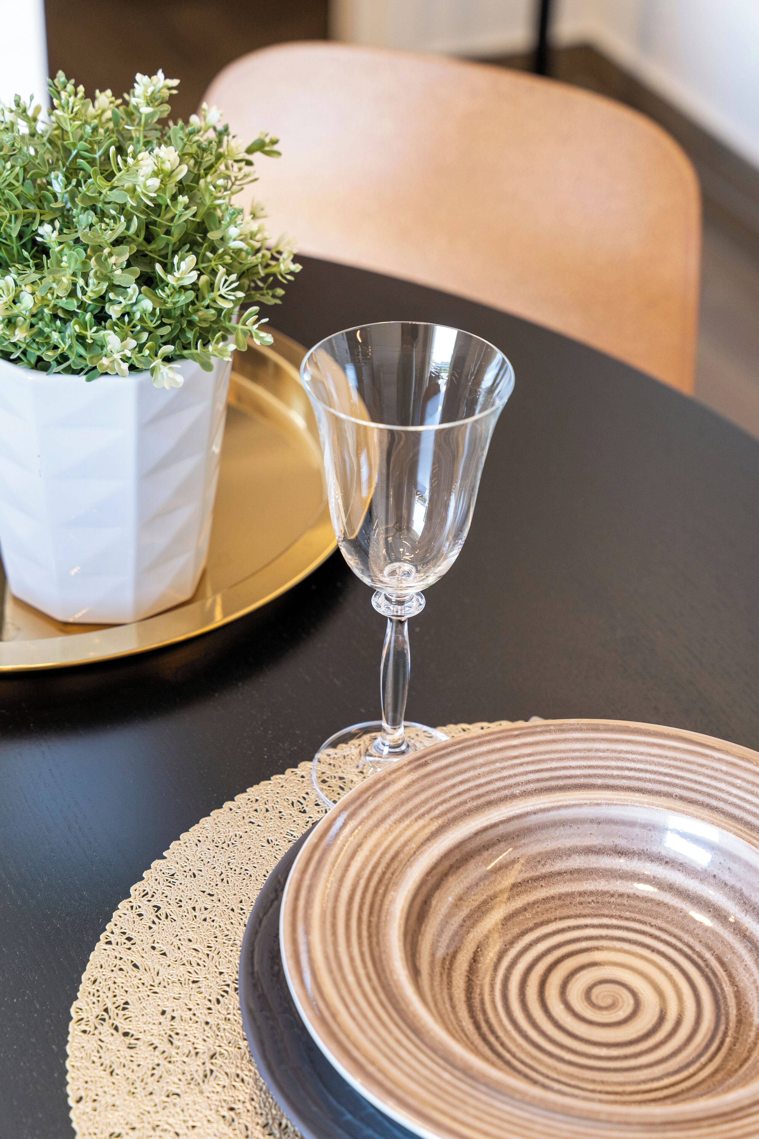 A table with a clear glass, a ceramic plate, and a potted plant.