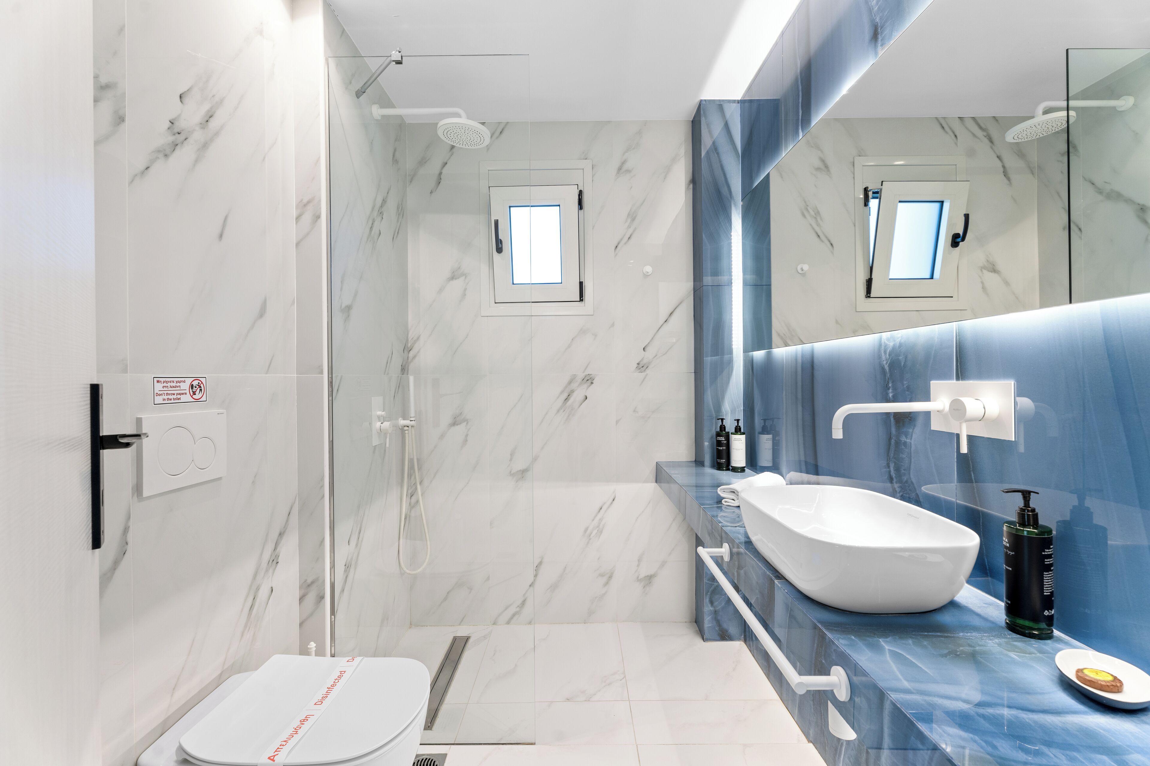 Une salle de bain moderne avec des toilettes blanches, un grand lavabo blanc et un espace douche.