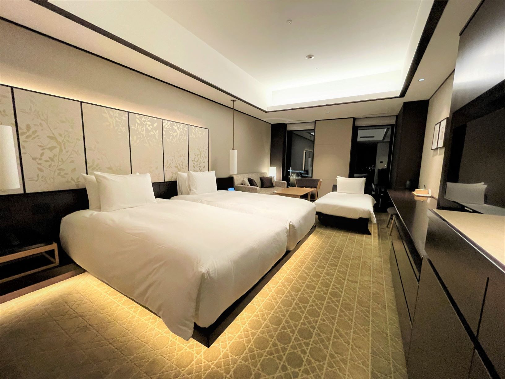 Una habitación de hotel moderna con una cama grande, un escritorio y un televisor.