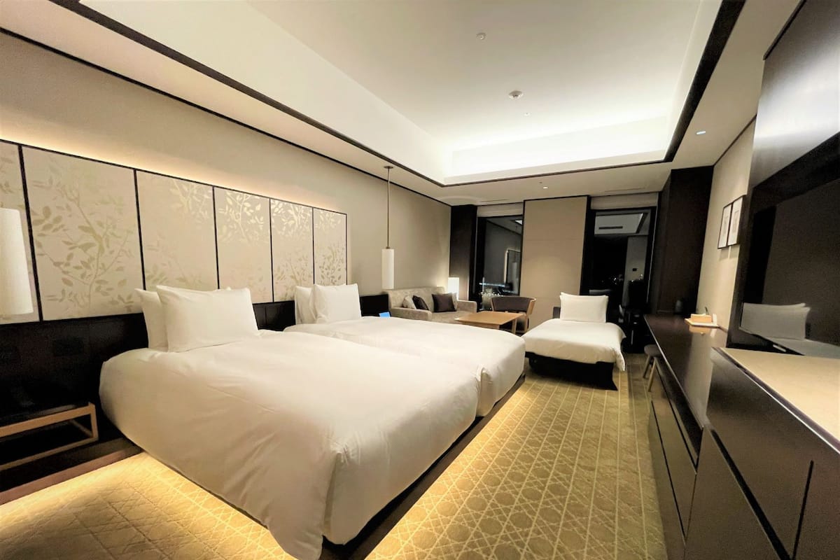 Ein modernes Hotelzimmer mit einem großen Bett, einem Schreibtisch und einem Fernseher.