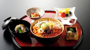 A variety of dishes on a tray, including a bowl of seafood, a bowl of soup, and a small dish with fruit.