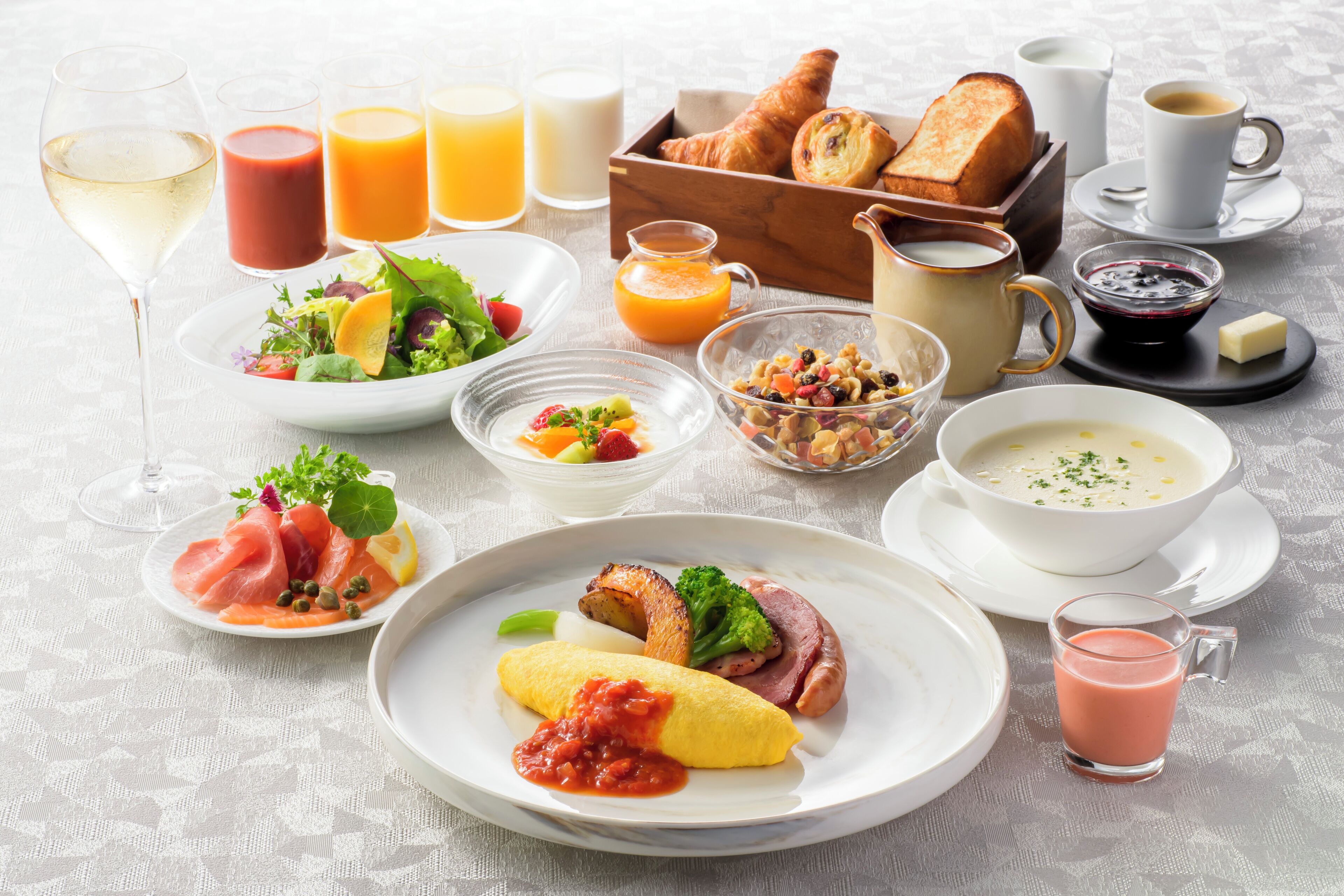 A breakfast setting with various dishes, drinks, and bread.