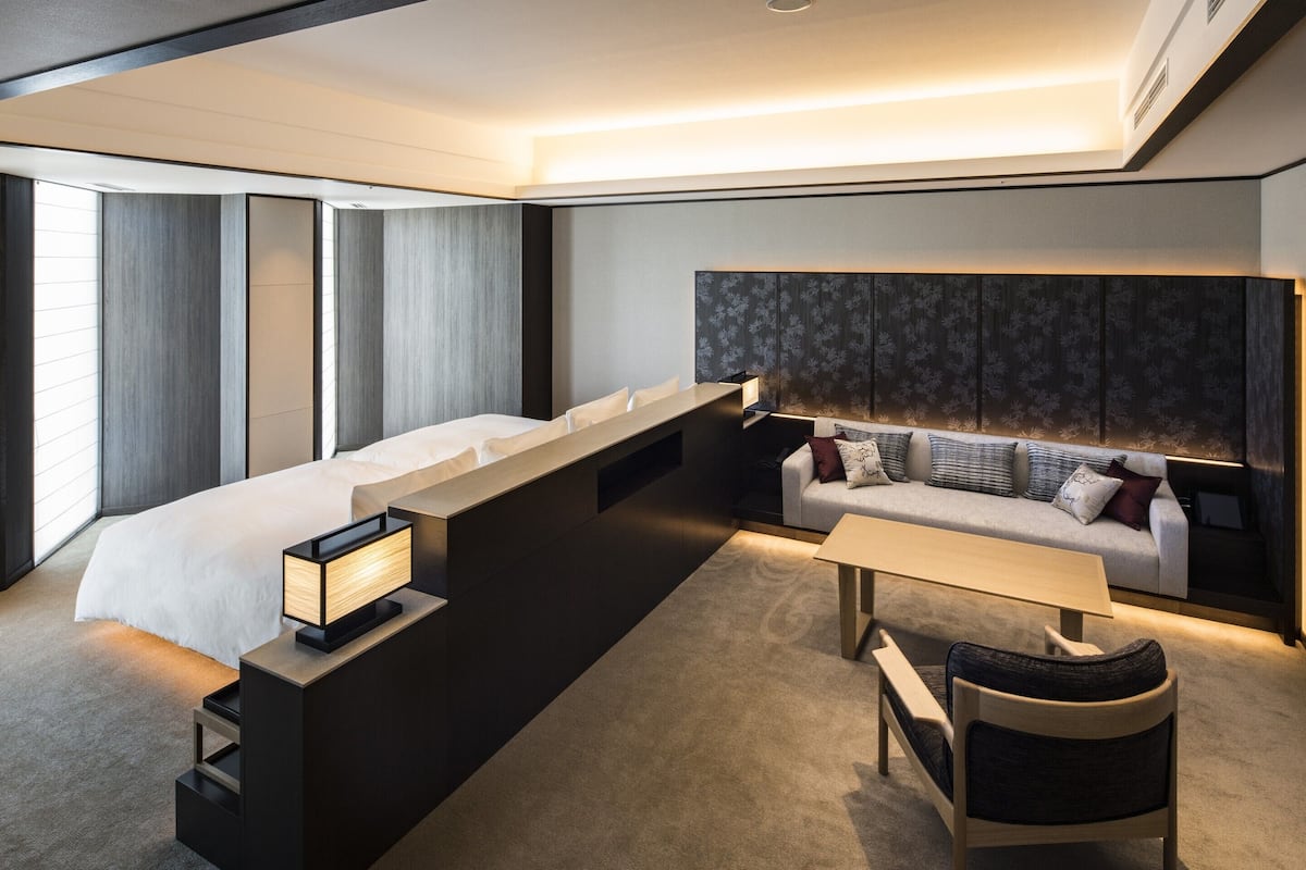 Ein modernes Hotelzimmer mit einem großen Bett, einer Couch, einem Schreibtisch und einem Sessel.