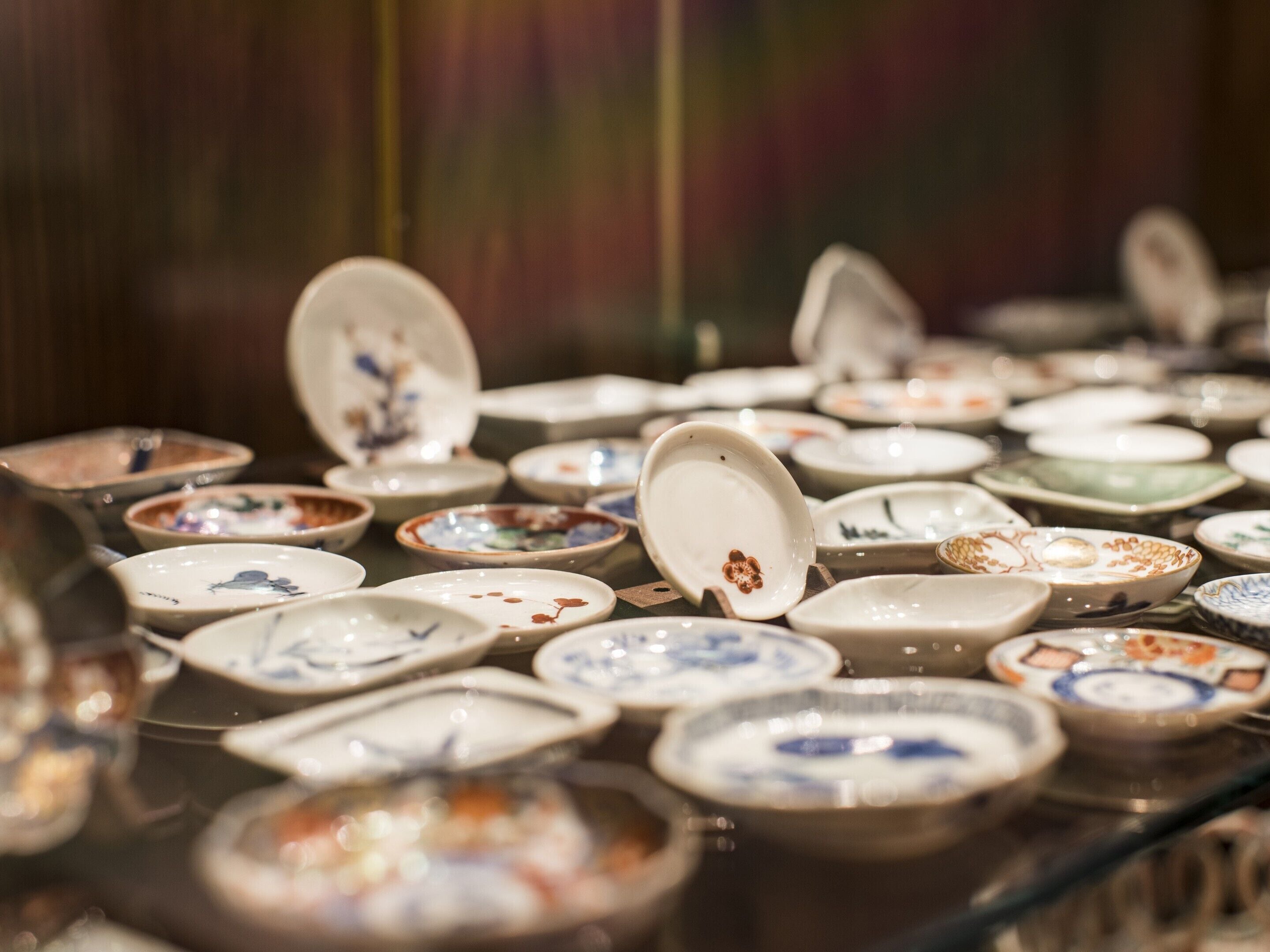 A display of various ceramic dishes with lids, arranged on a glass surface.