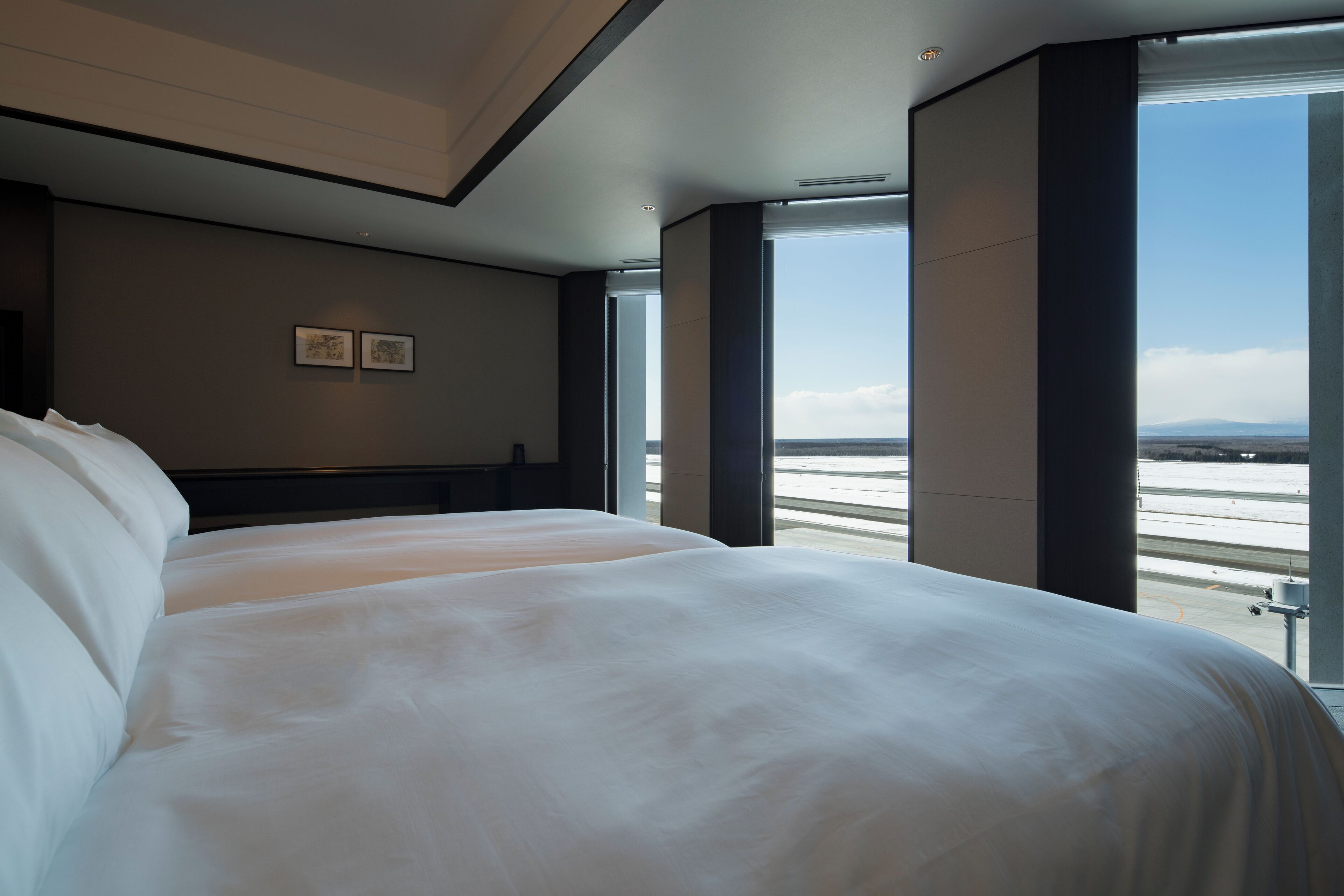 A large bed in a hotel room with a view of the airport.