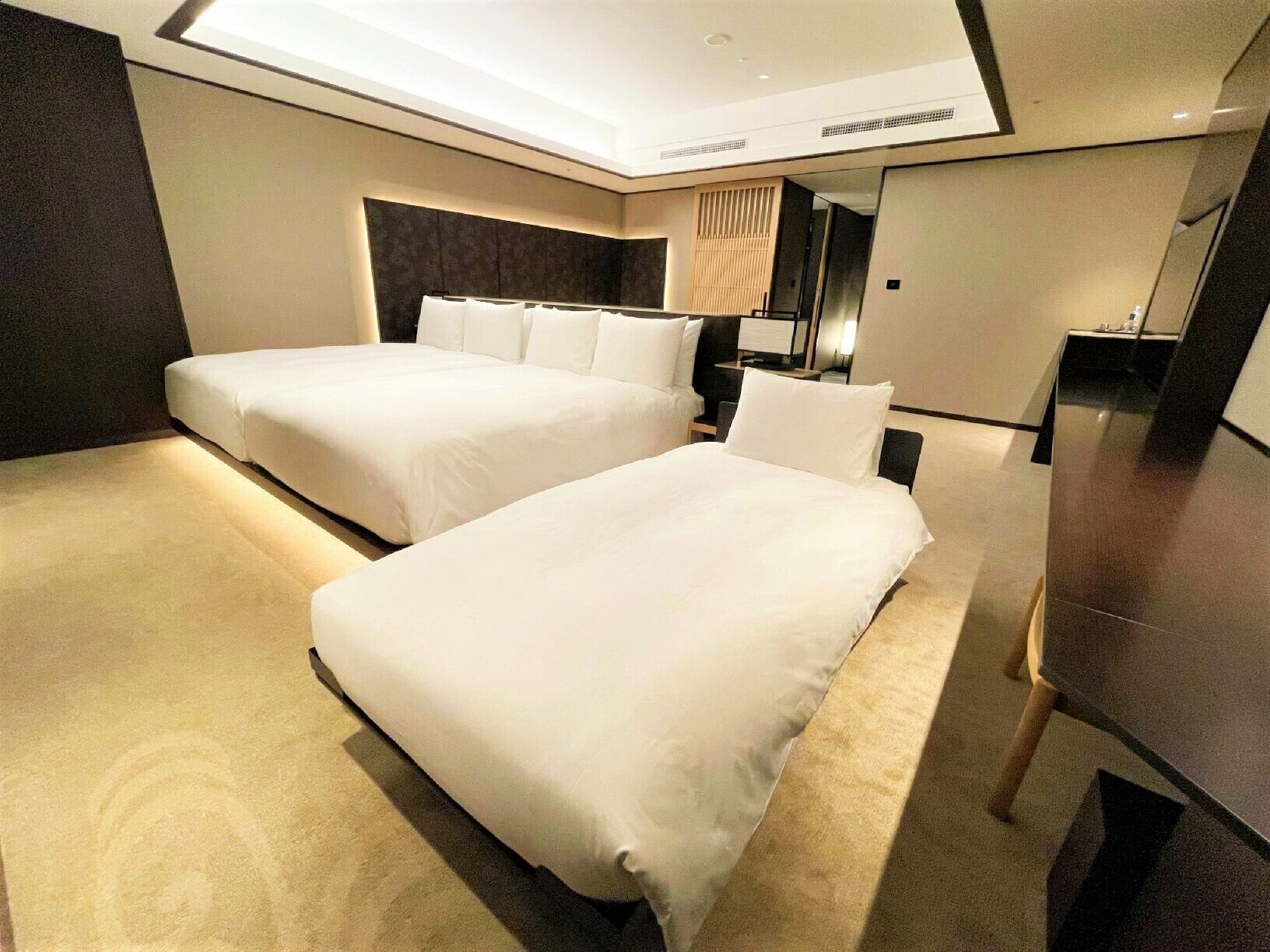 Una habitación de hotel con dos camas, un escritorio y un espejo.