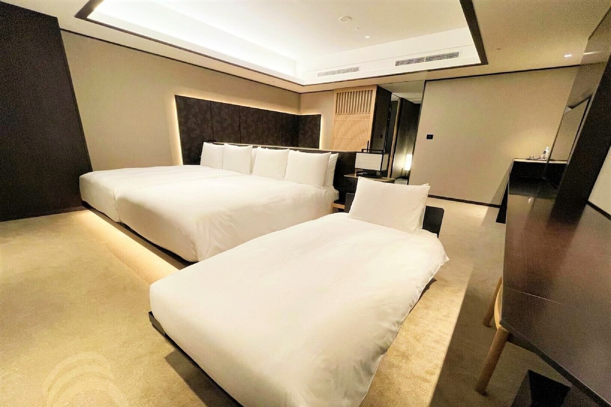 Ein Hotelzimmer mit zwei Betten, einem Schreibtisch und einem Spiegel.