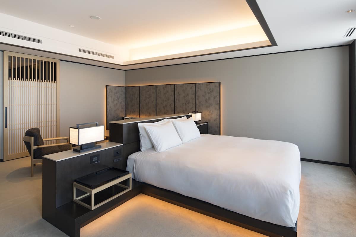 Ein modernes Hotelzimmer mit einem großen Bett, Nachttischen, einem Schreibtisch und einem Sessel.