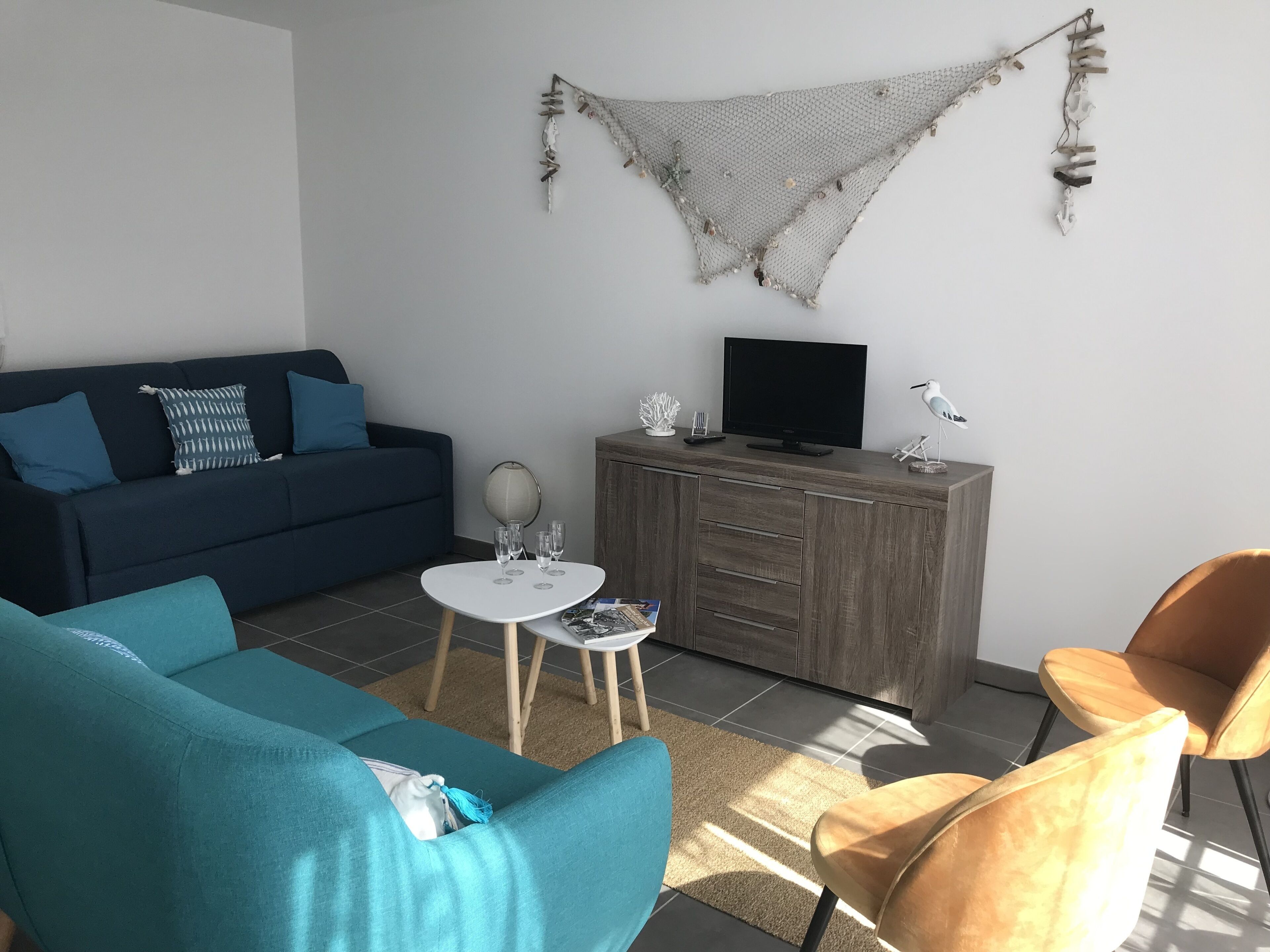 Een woonkamer met een bank, een salontafel, een televisie en een kast.