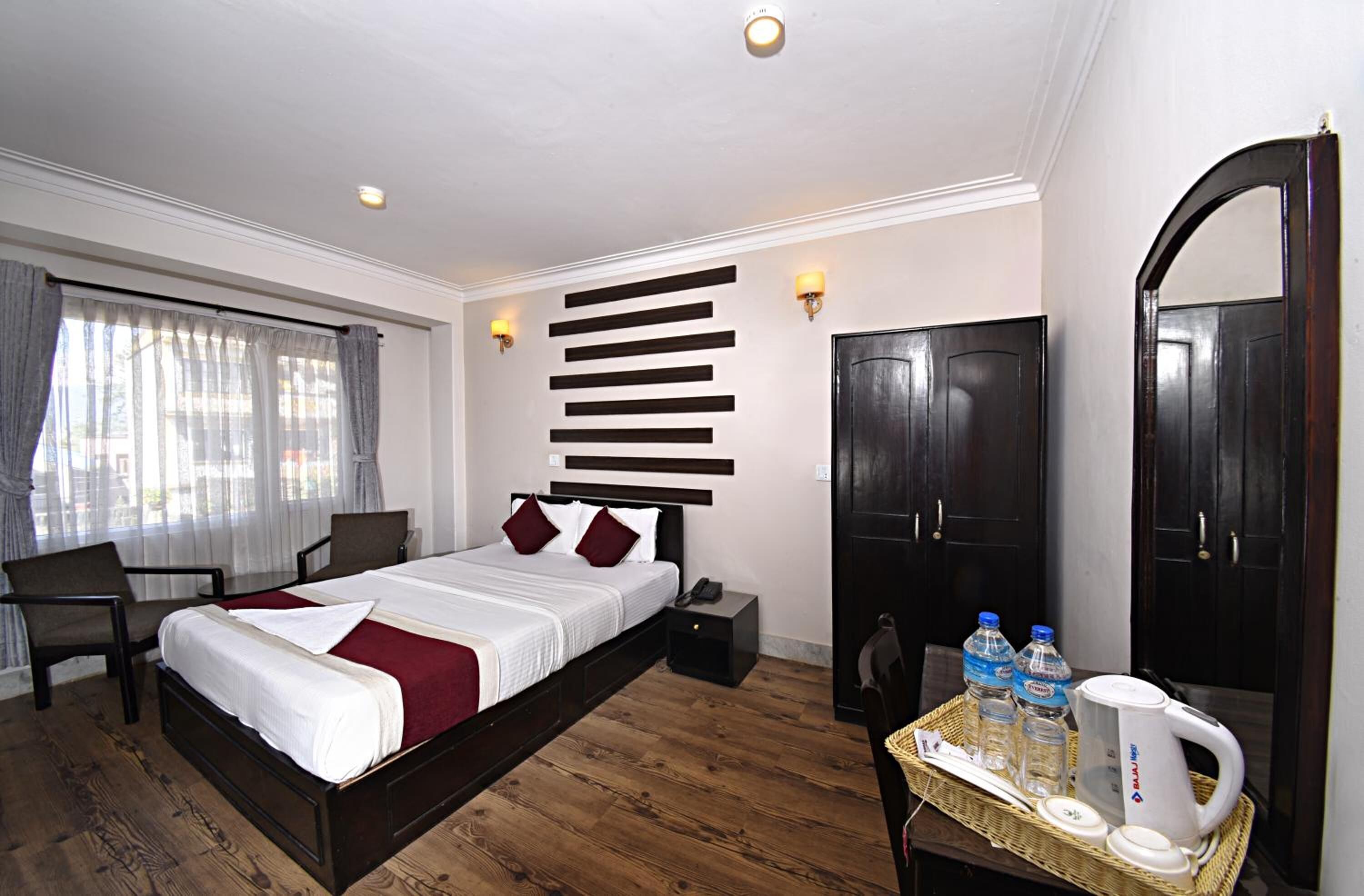 A hotel room with a bed, bedside table, wardrobe, and a mirror.