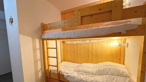A bunk bed with a ladder, wooden headboard, and a white mattress. - Studio for 4 in Ménuires, renovated, mountain view (Les Menuires)