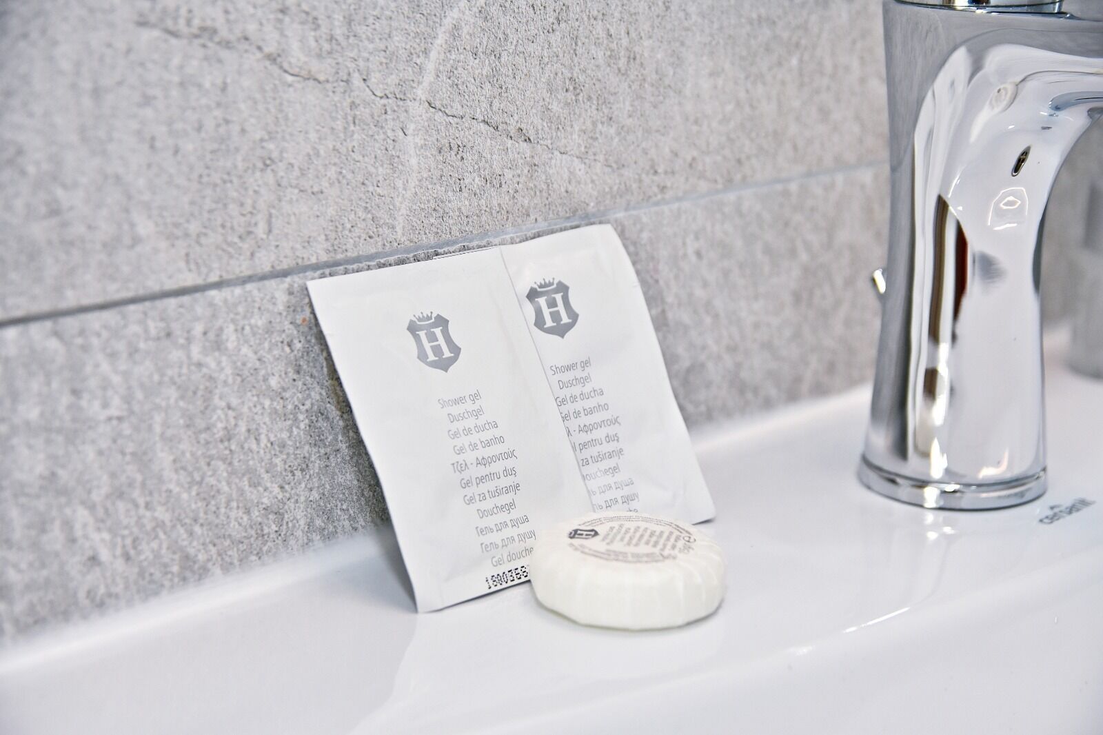 A bathroom with a white sink, a faucet, and a shower gel package with text in a foreign language.