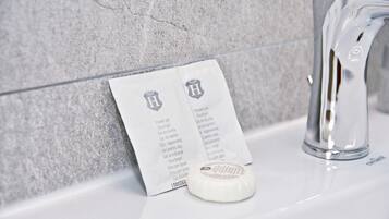 A bathroom with a white sink, a faucet, and a shower gel package with text in a foreign language.