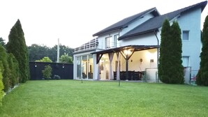 A house with a large lawn, a covered patio, and a garage. - Green Wood Residence (Ghiroda)
