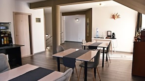 A hotel room with a kitchenette, a dining area, and a staircase leading to another room. - Green Wood Residence (Ghiroda)
