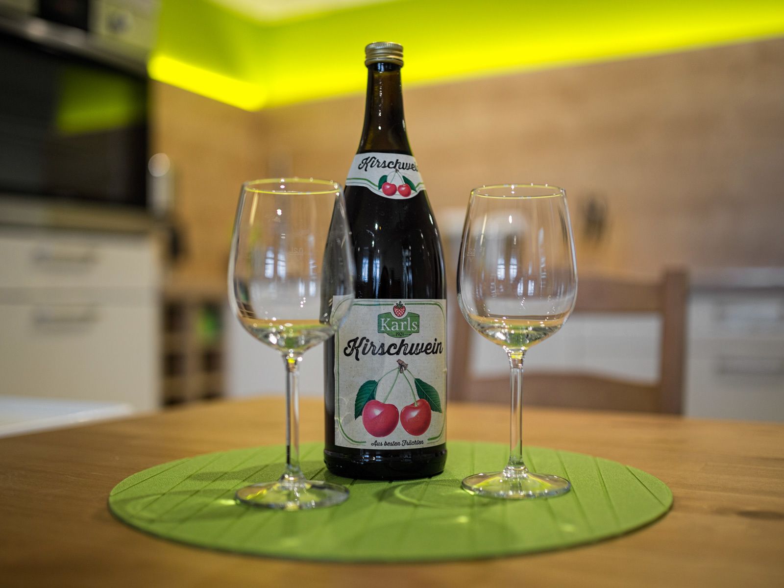Una botella de Kirschwein y dos vasos sobre una mesa.