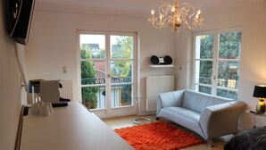 Ein modernes Schlafzimmer mit einem weißen Schreibtisch, einem grauen Sofa, einem roten Teppich und einer Kristallleuchter.