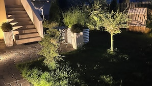 Ein Wohnbereich im Freien mit einem gepflasterten Weg, einer Treppe und verschiedenen Pflanzen und Sträuchern.