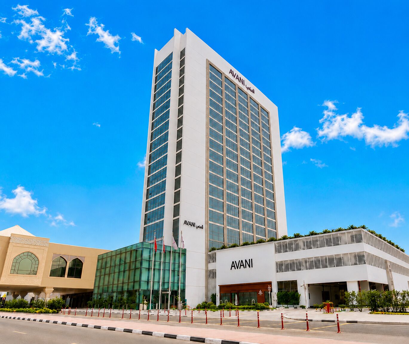 A tall, modern building with the name 'AVANI' on the facade, featuring a glass facade and a flat roof.