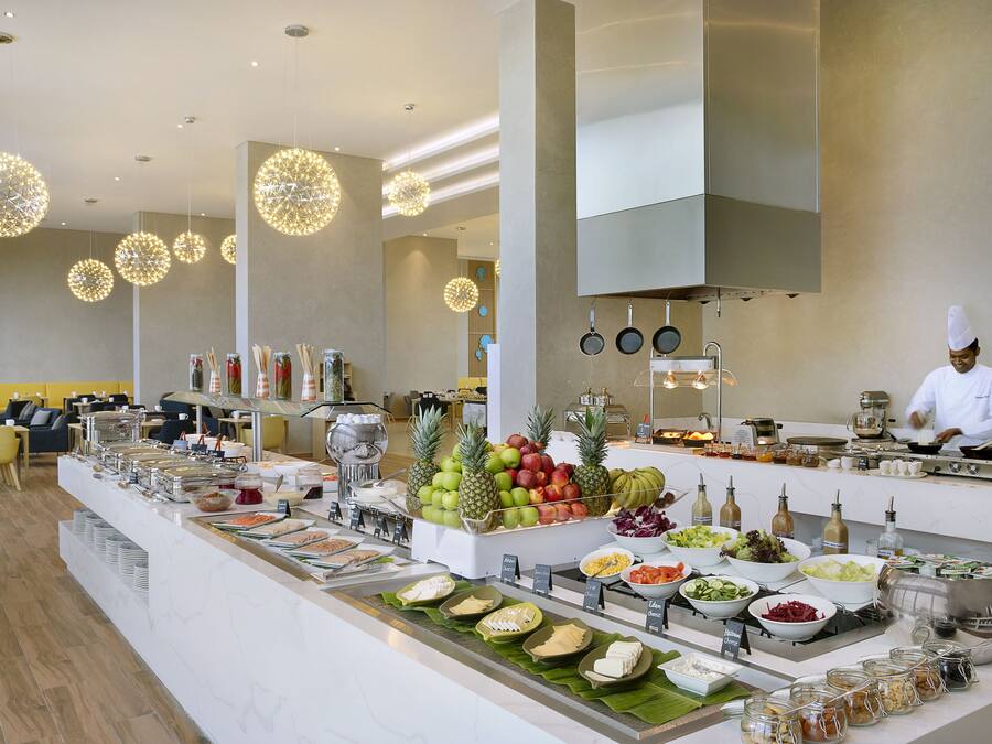 Uma área de buffet com diversos pratos e um chef preparando refeições.