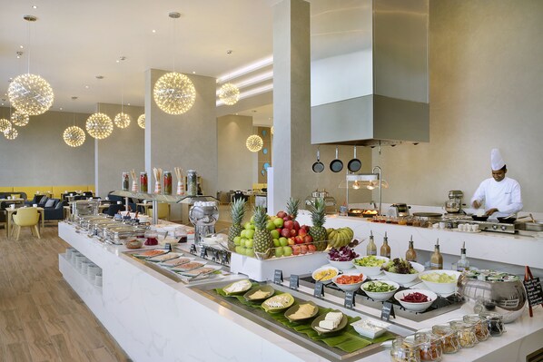 A buffet area with a variety of food items and a chef preparing food.
