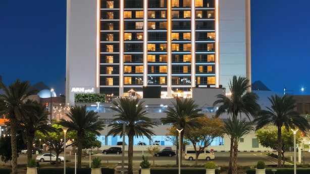 Un edificio alto con un letrero llamativo que dice 'AVANI' en la parte superior.