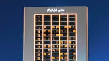 Um edifício alto com uma placa grande exibindo 'AVANI' no topo.