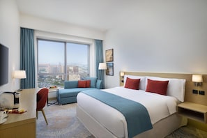 A hotel room with a large bed, a sofa, a desk, and a view of the city. - Avani Ibn Battuta Dubai Hotel (Dubai)