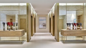 A hallway with mirrored walls, a central artwork, and two wooden tables with vases. - Avani Ibn Battuta Dubai Hotel (Dubai)